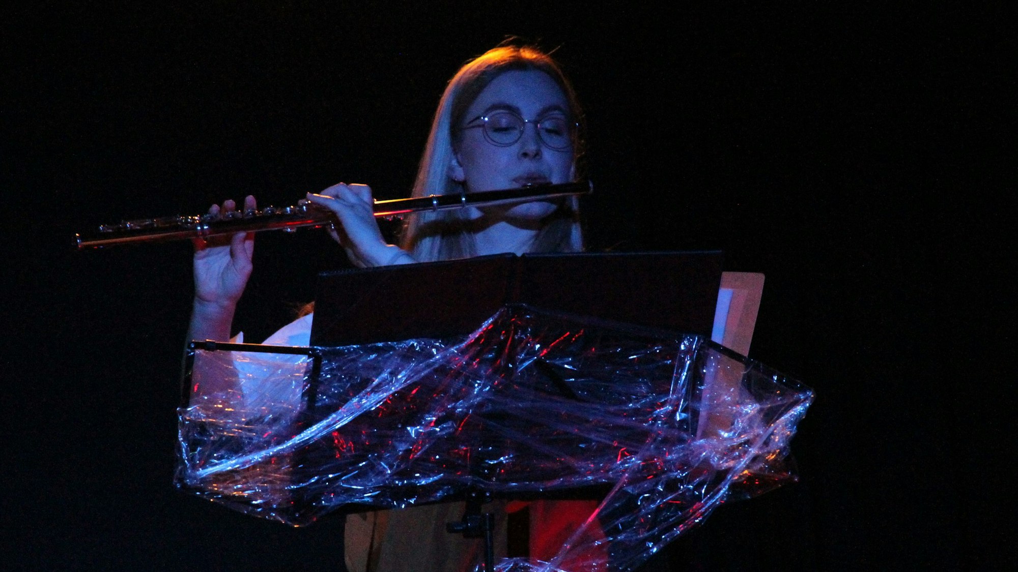 Eine Frau an einem Notenpult spielt Querflöte