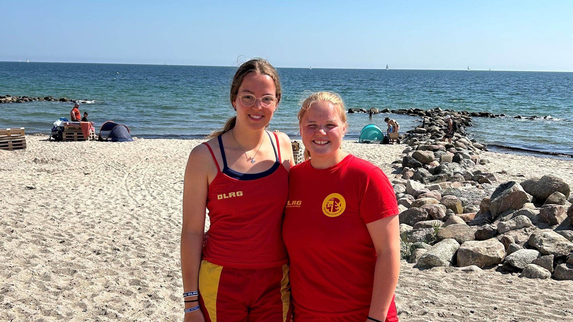 Zwei Frauen in der Uniform der Rettungsschwimmer stehen am Strand.