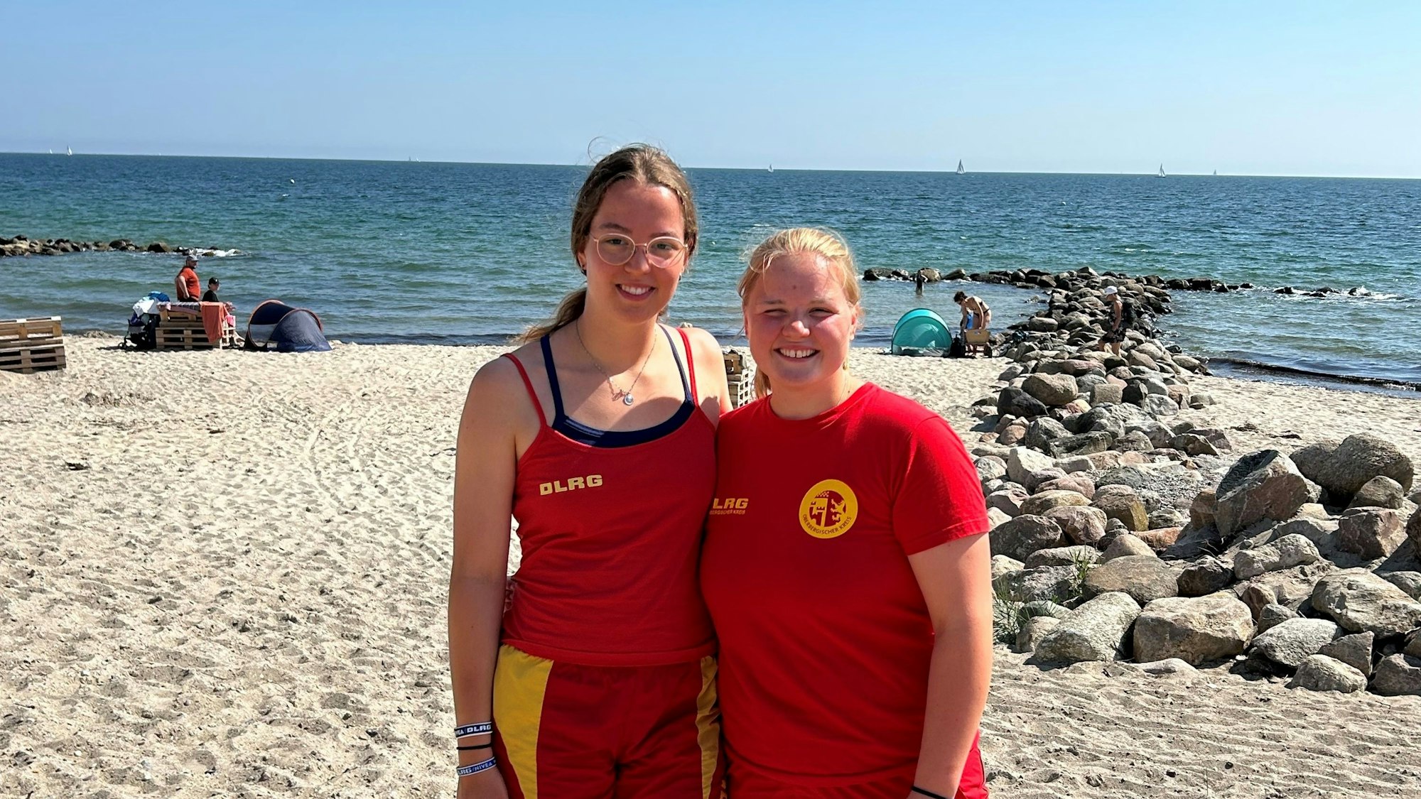 Zwei Frauen in der Uniform der Rettungsschwimmer stehen am Strand.