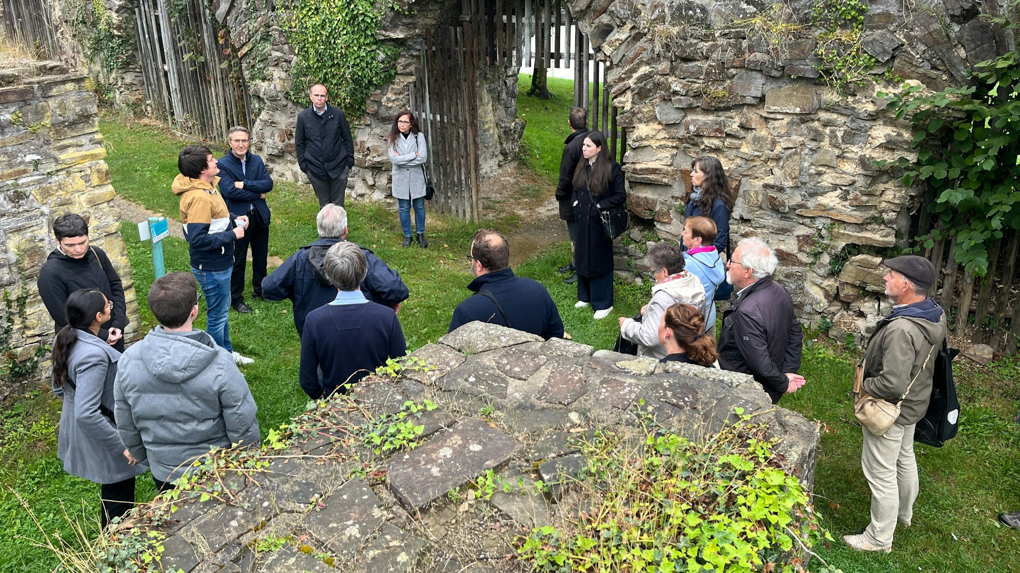 Politiker und Verwaltungsmitarbeiter stehen zwischen zwei Mauerstücken in Stadt Blankenberg.