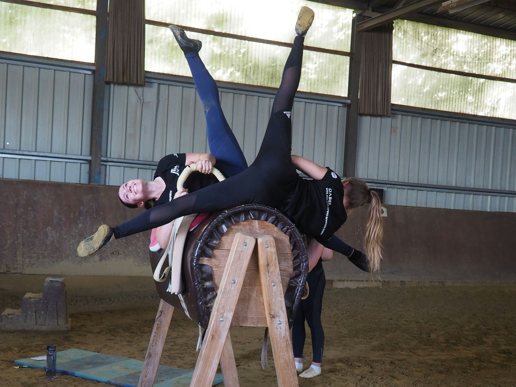 Zwei Voltigiererinnen trainieren auf dem Übungspferd.