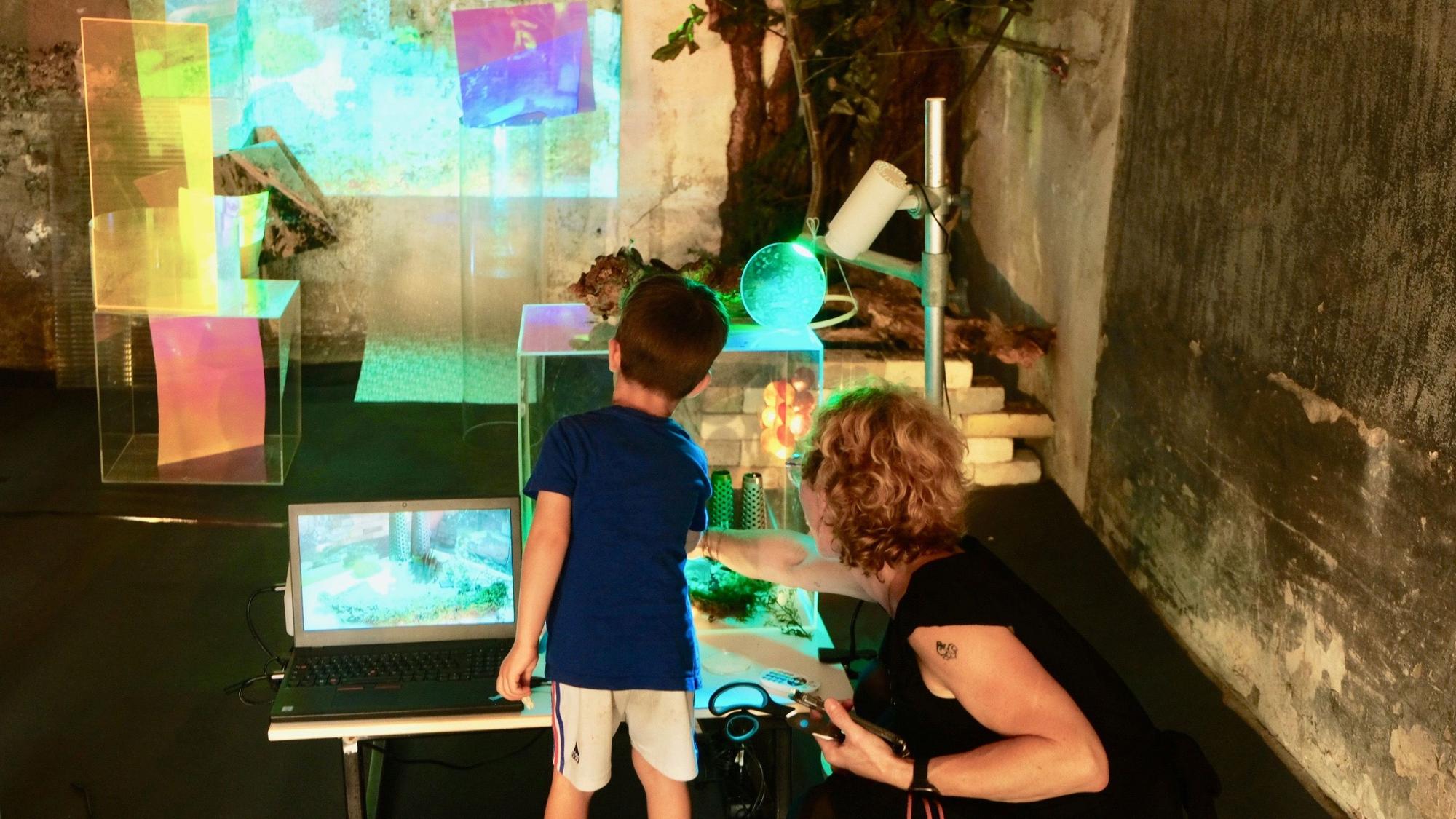 Ein junger Besucher erforscht an einer Ausstellungsstation Materialien und digitale Möglichkeiten.