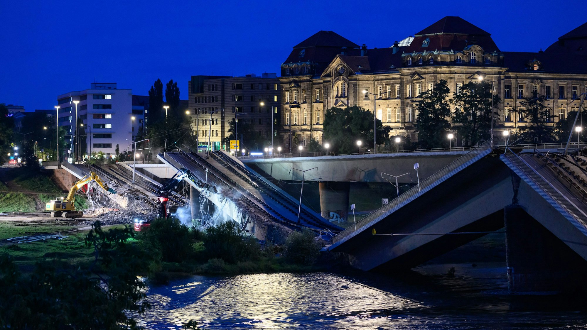 dpatopbilder - 13.09.2024, Sachsen, Dresden: Mit Baggern werden weitere Teile der eingestürzten Carolabrücke abgerissen, dahinter ist die Staatskanzlei zu sehen. Im Zuge von Abrissarbeiten ist ein weiterer Abschnitt der Carolabrücke in Dresden eingebrochen. Es handelt sich um den Brückenstrang mit Straßenbahngleisen, der in der Nacht zum Mittwoch bereits teilweise in die Elbe gestürzt war. Foto: Robert Michael/dpa +++ dpa-Bildfunk +++