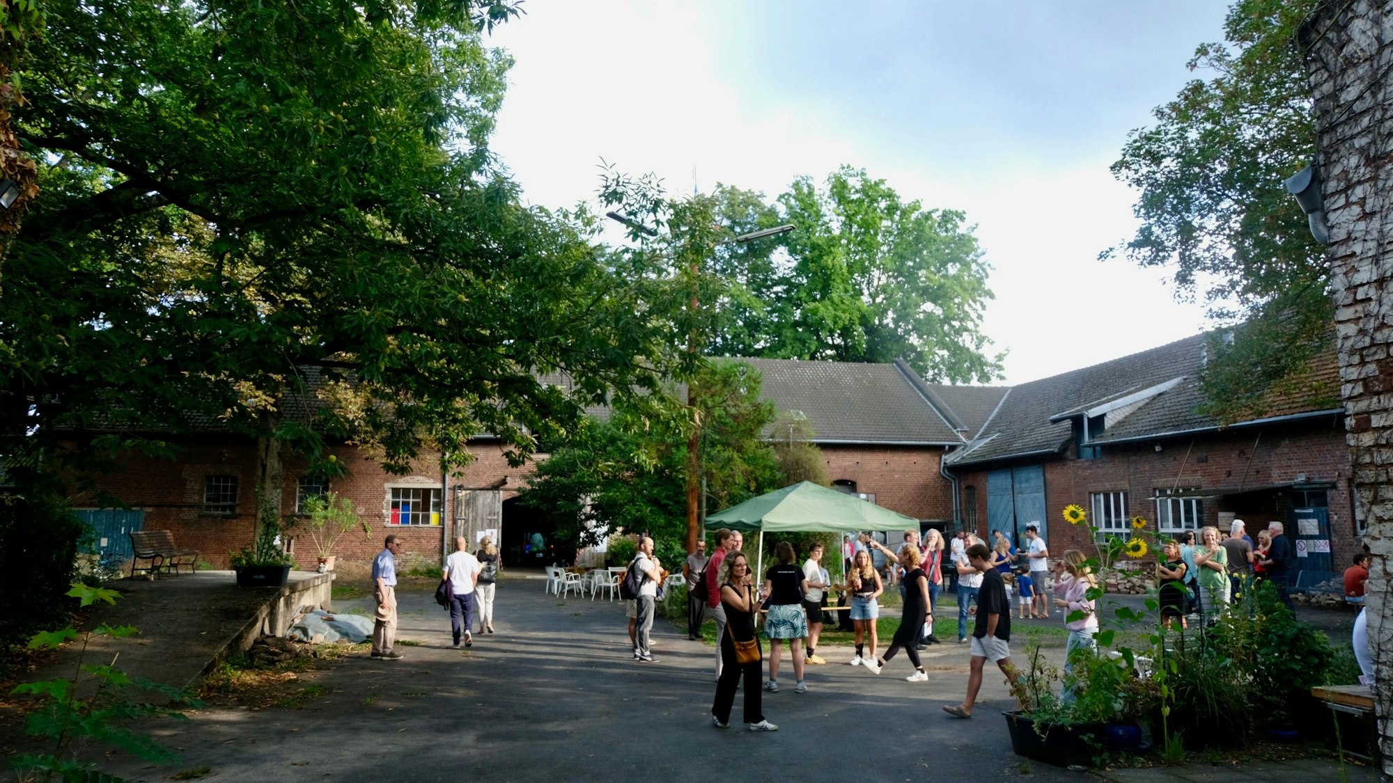 Im Innenhof eines Gutshofs tummeln sich Menschen.