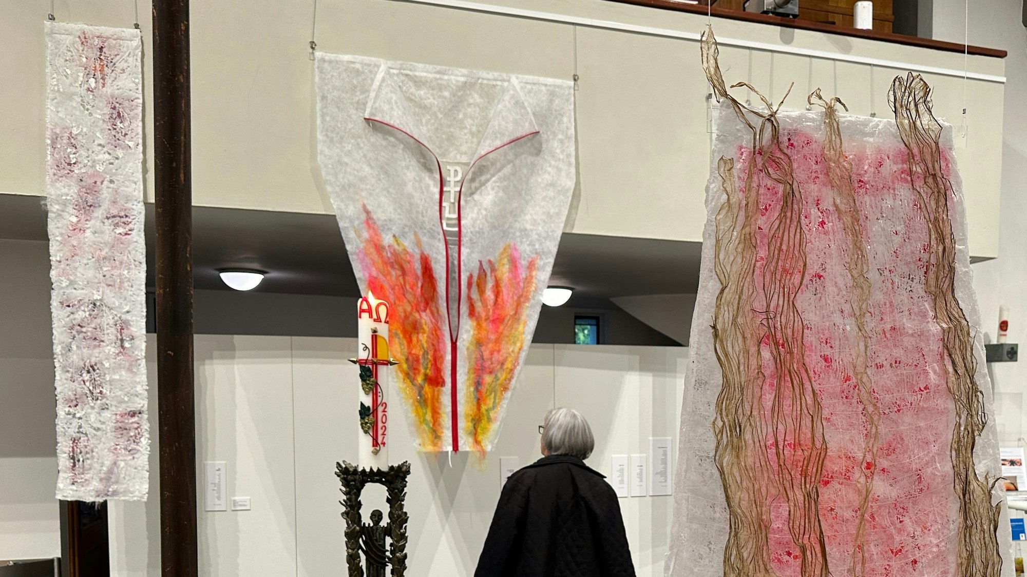Eine Besucherin betrachtet einen bemalten Textilvorhang.