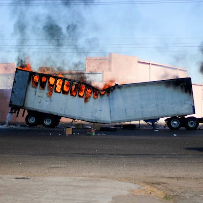 Männer fahren am 4. Januar 2023 auf einem Motorrad an einem brennenden Lastwagen in den Straßen von Culiacán im Bundesstaat Sinaloa vorbei.
