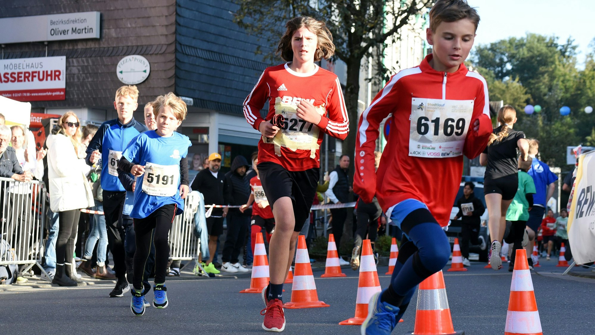 Zu sehen sind vünf Schüler, die über eine Straße laufen.
