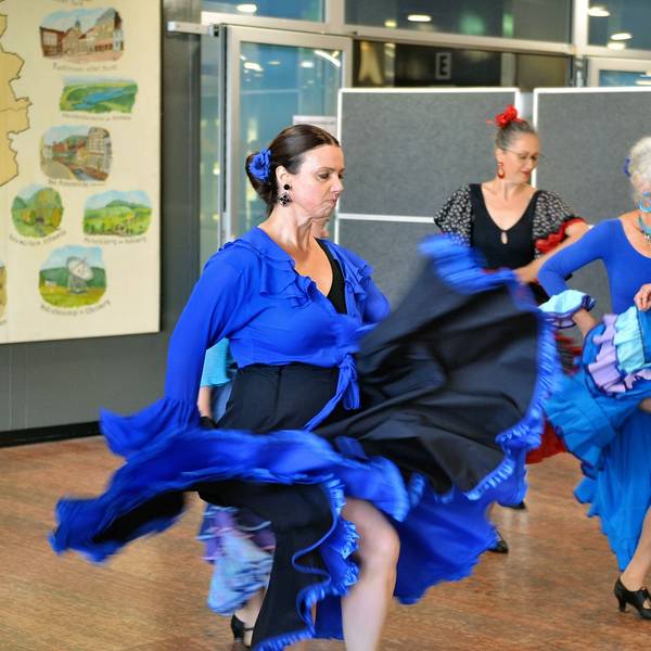 Drei Frauen mit Flamenco-Kleidern und ernstem Gesichtsausdruck zeigen einen Tanz.
