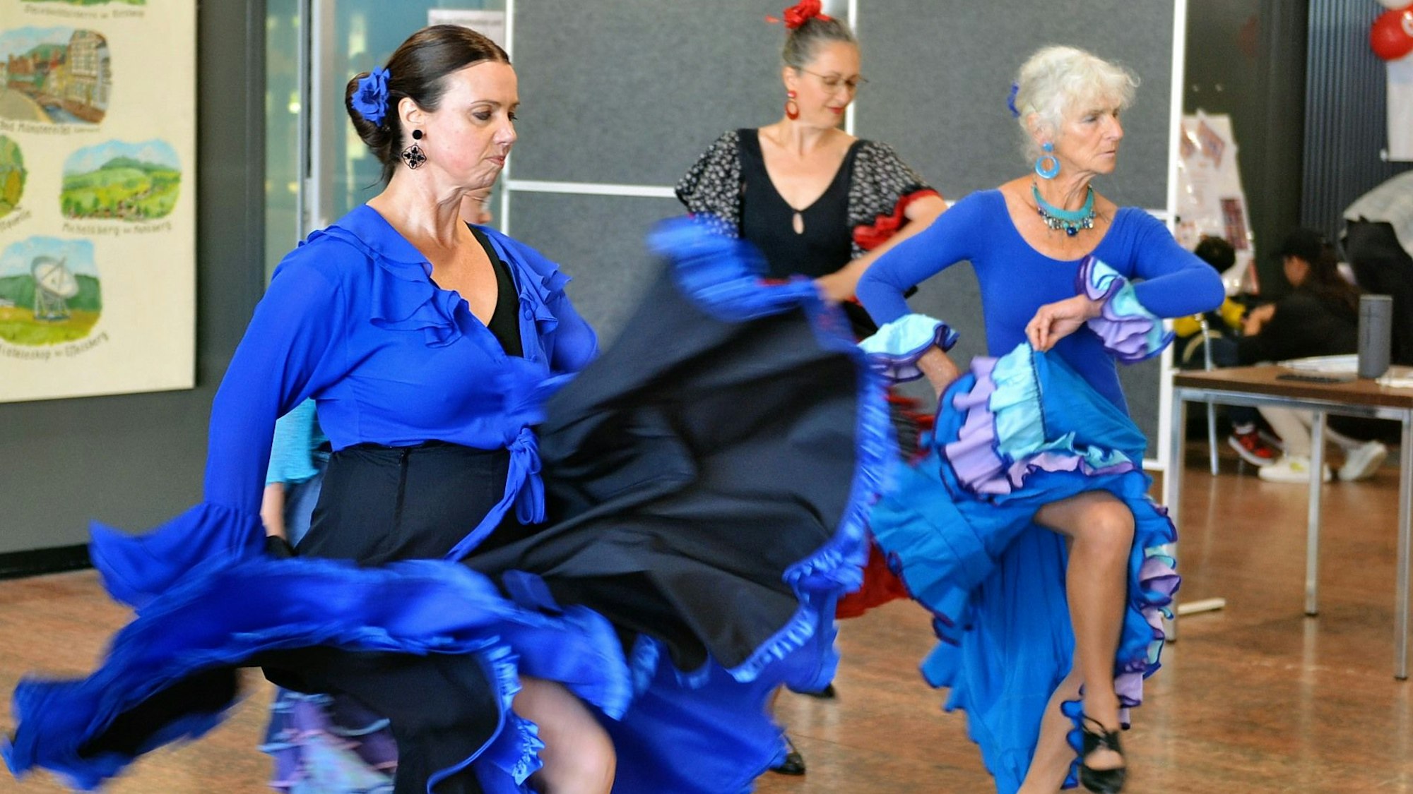Drei Frauen in traditionellen spanischen Kleidern tanzen Flamenco.