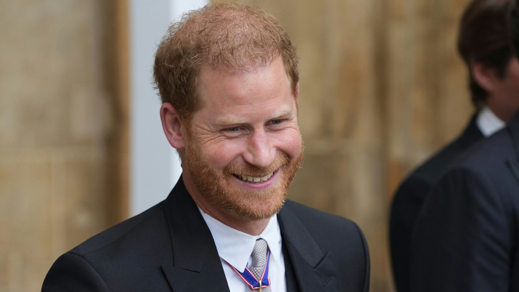 Prinz Harry, Herzog von Sussex, verlässt nach der Krönung von König Charles III. und Königin Camilla die Westminster Abbey und lächelt.