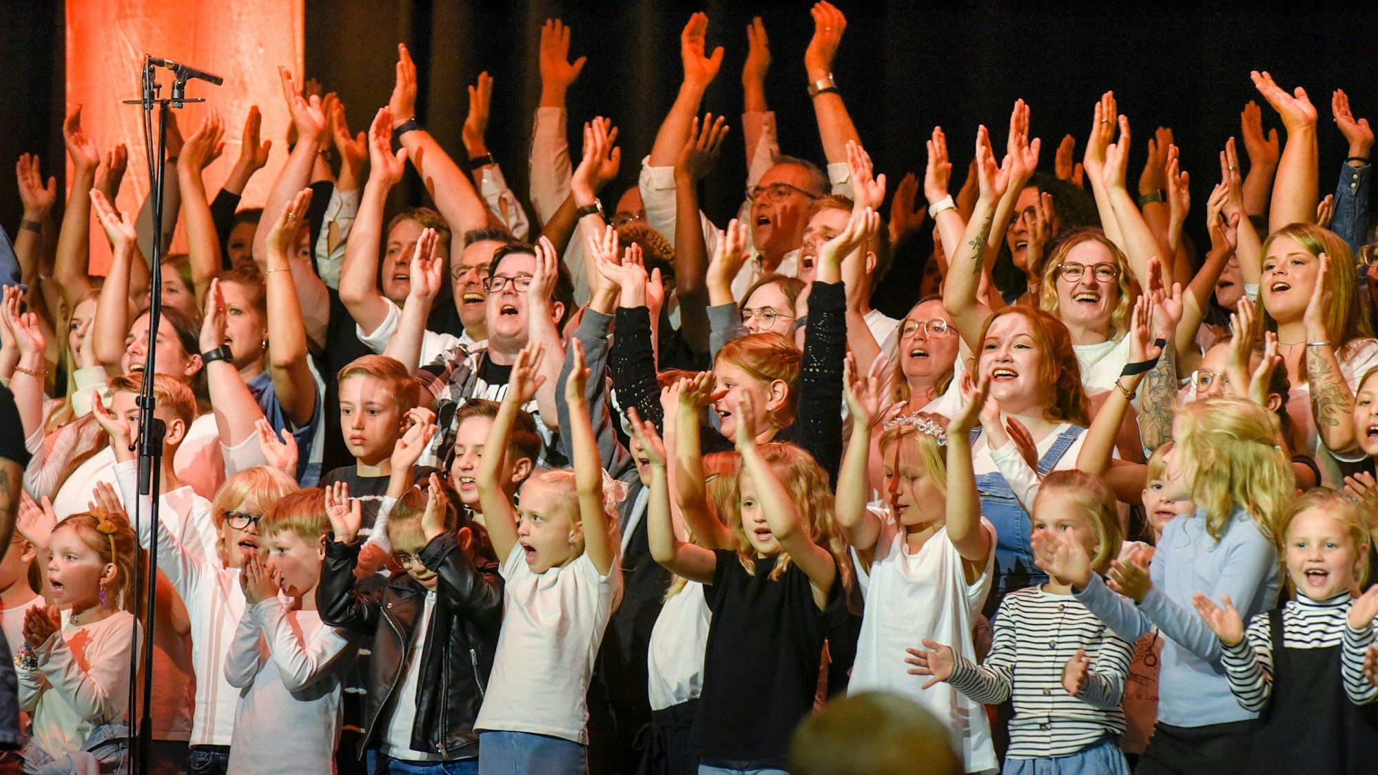 Zahlreiche Kinder und Erwachsene werfen die Arme in die Luft.