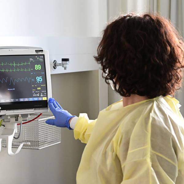 Eine Pflegerin schaut in einem Krankenzimmer im Klinikum Stuttgart auf einen Monitor einer Patientin.