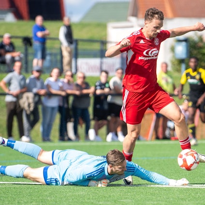 Mit ausgebreiteten Armen läuft ein Fußballer, den Blick nach unten gerichtet.