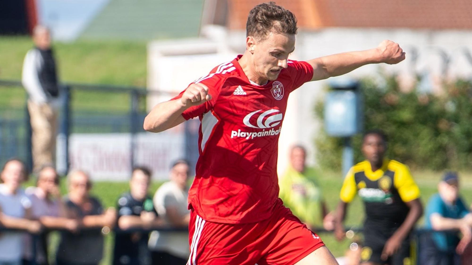 Mit ausgebreiteten Armen läuft ein Fußballer, den Blick nach unten gerichtet.