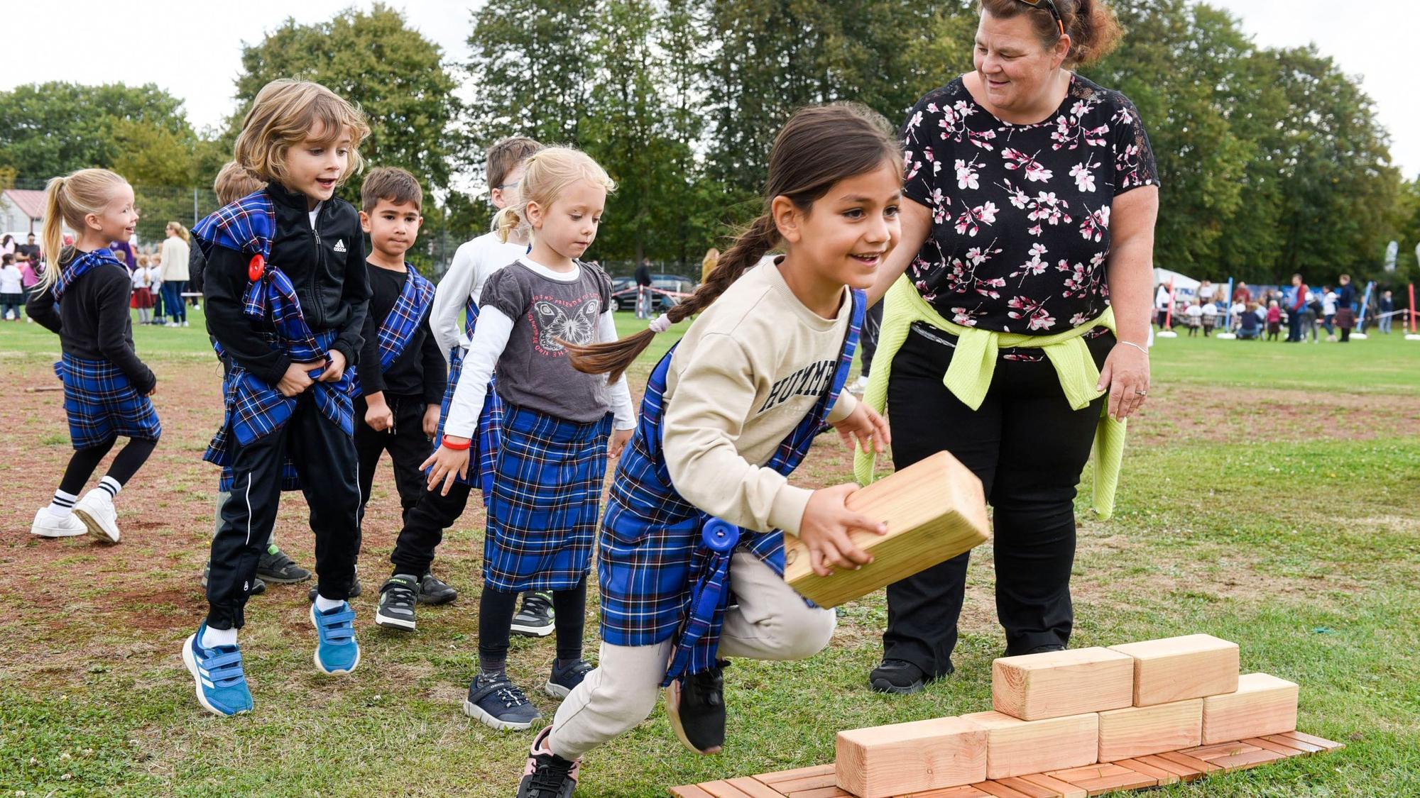 Kinder bauen eine Pyramide aus Holzklötzen.