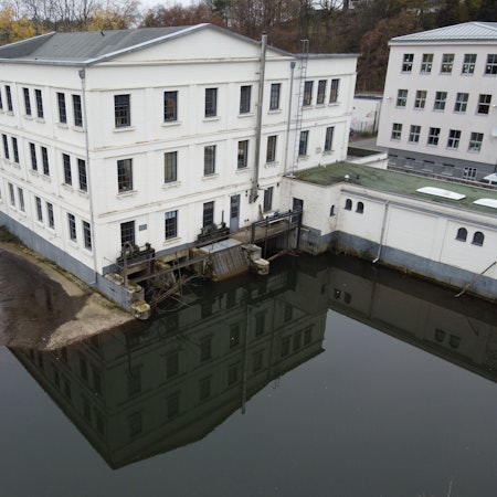 Das Foto zeigt das Alte Turbinenhaus an der Wupper mitsamt dem Wehr.