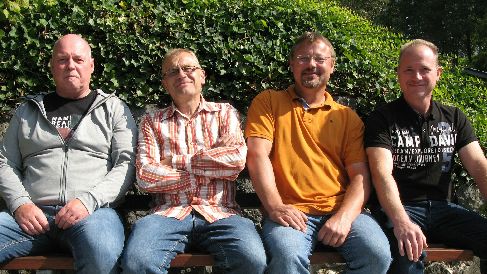 Vier Männer der Dorfjugend Hanfmühle sitzen auf einer Bank.