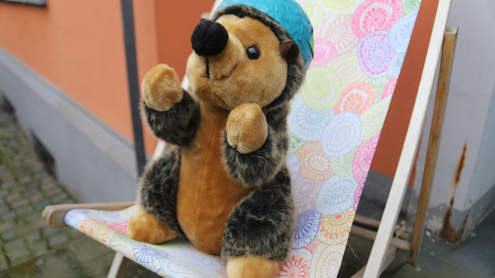 .Ein Stoffigel sitzt auf einem Liegestuhl