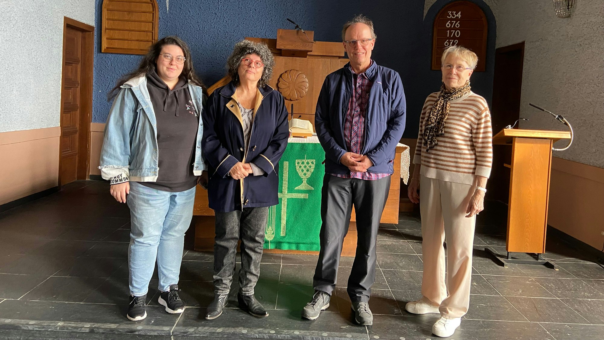 Drei Frauen und ein Mann stehen vor einem Altar in einer Kirche.