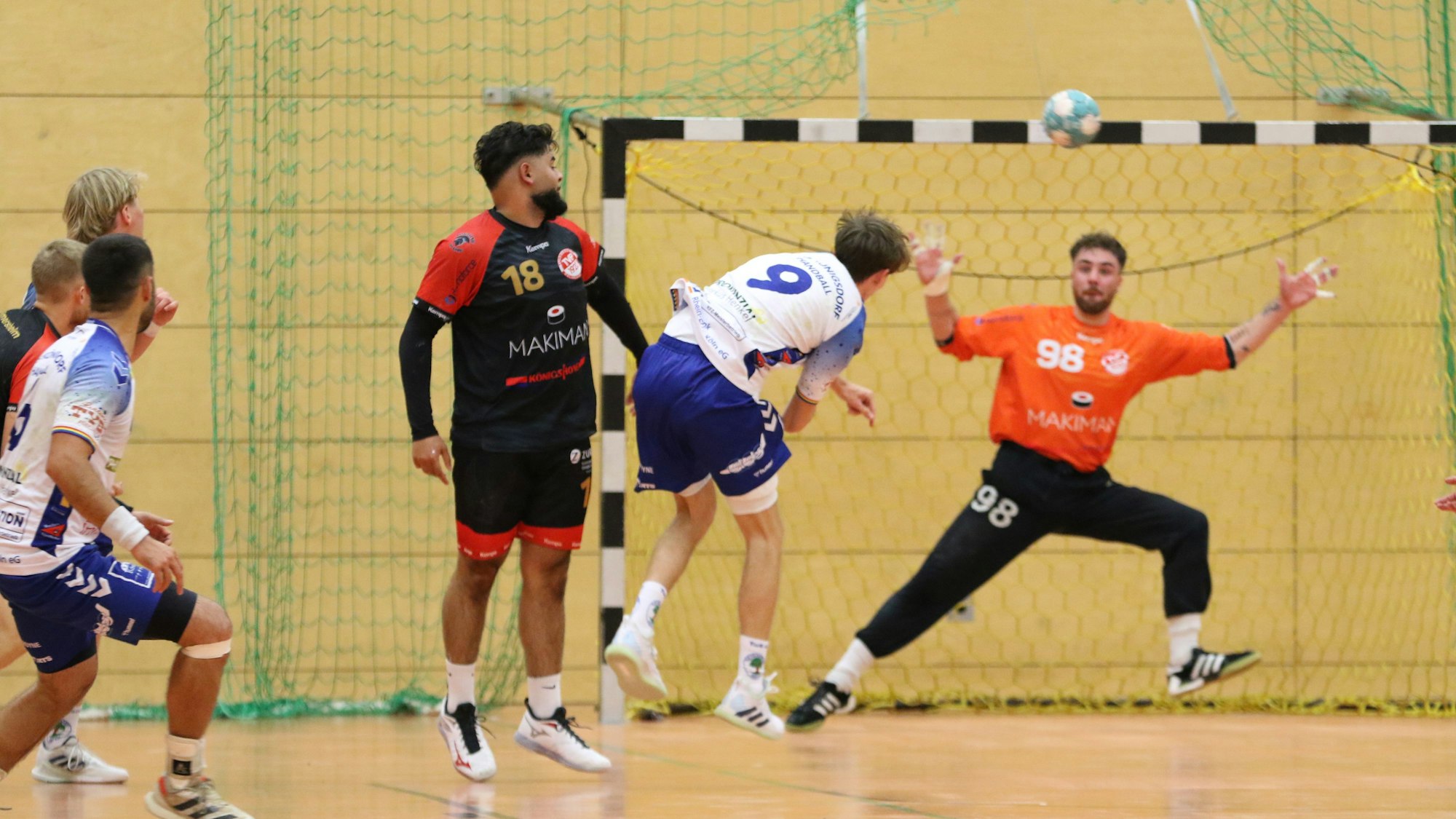 Ein Königsdorfer Angreifer hat auf das Tor geworfen, der Ball ist noch in der Luft. Der Torwart fixiert ihn mit den Augen, um ihn abzuwehren.