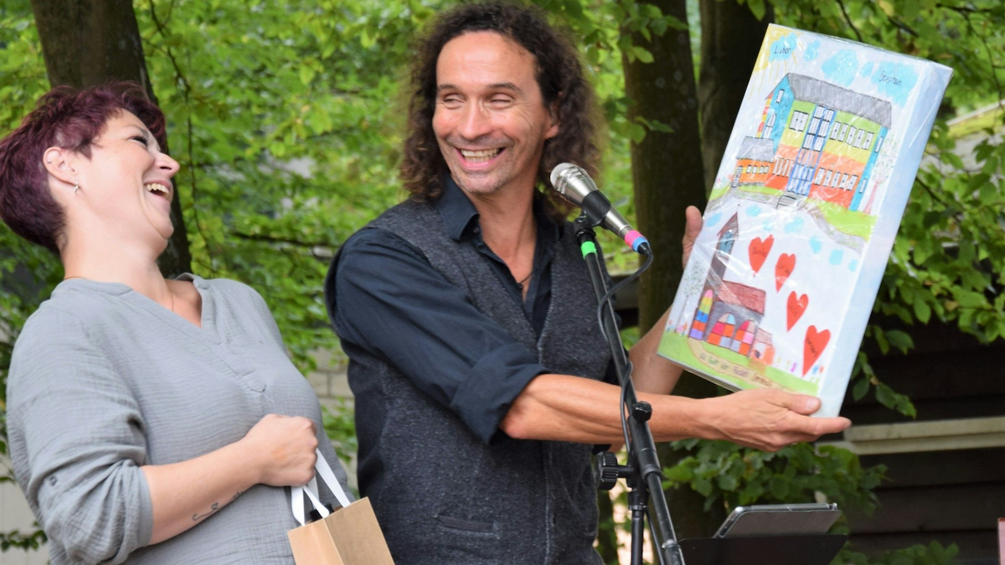 Jasmin Heller überreicht dem Musiker Stefan Brings das von den OGS-Kindern gemalte Bild.