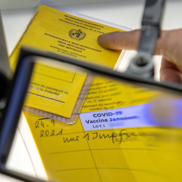 Ein Impfpass unter der Lupe mit dem Eintrag einer Corona-Impfung