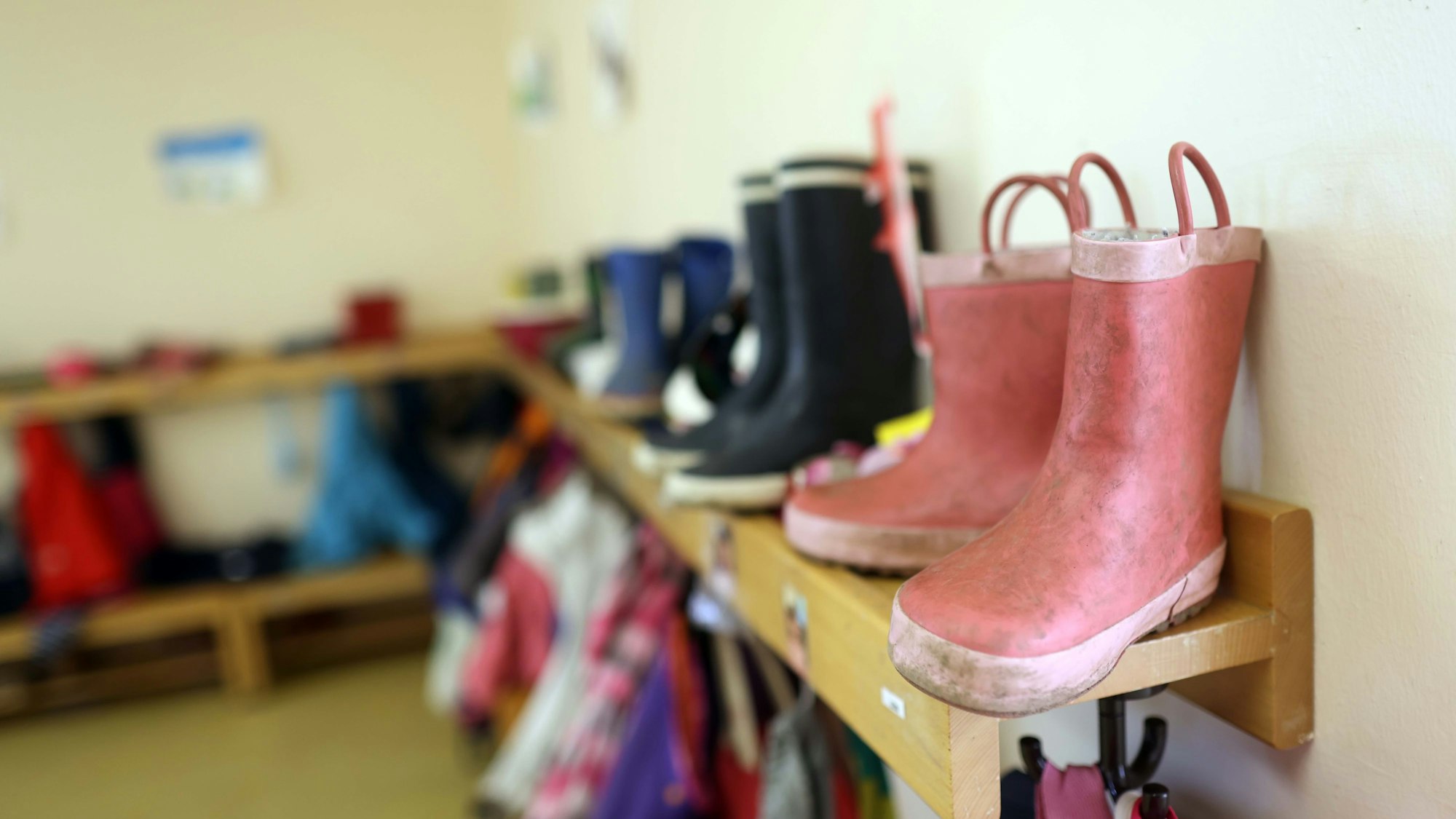 Kinder-Gummistiefel stehen auf einem Regal.