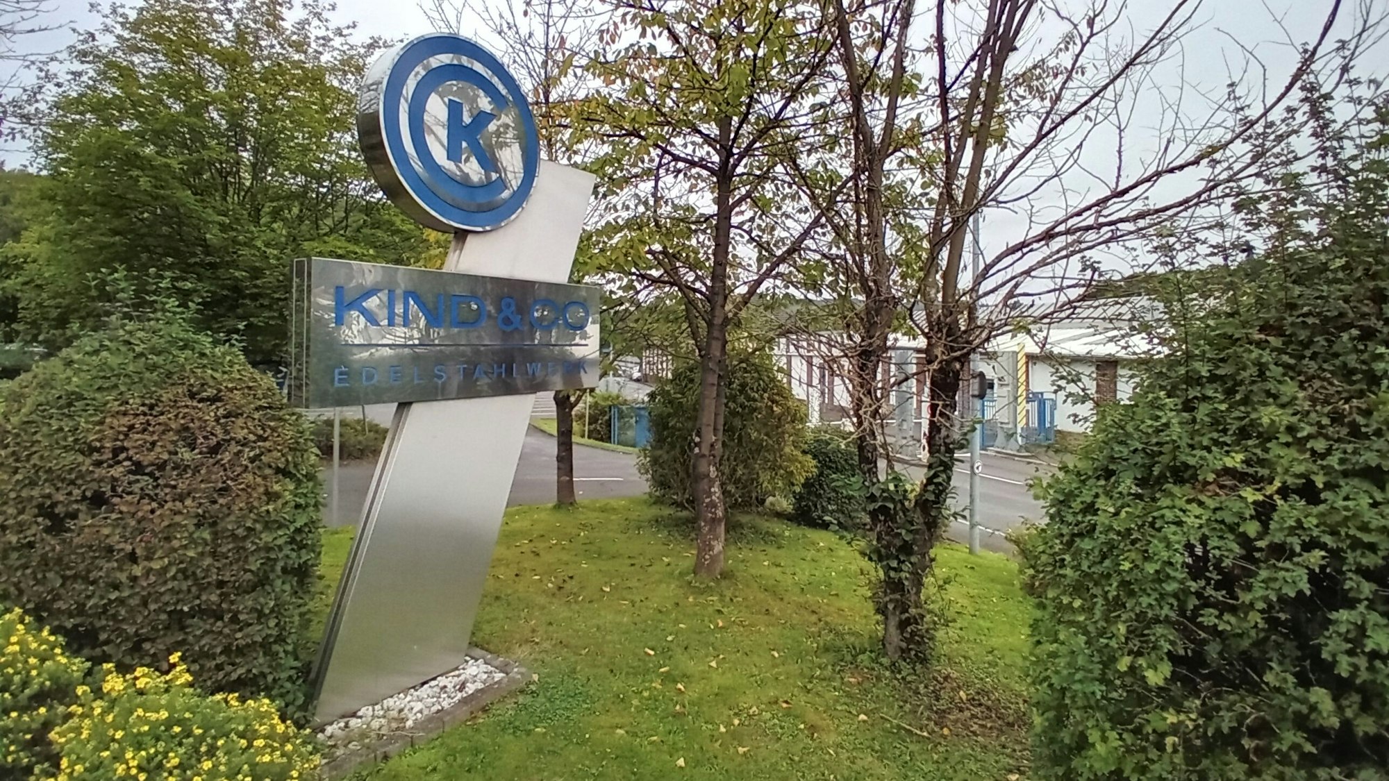 Eine Stele mit dem Firmennamen „Kind & Co.“ vor dem Werkstor.