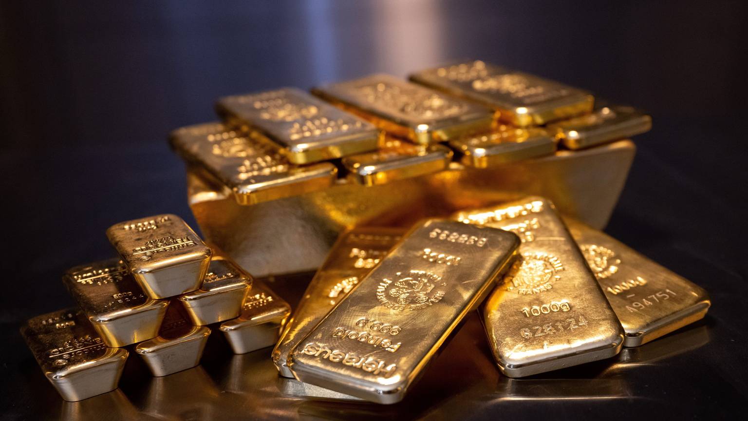 Goldbarren in unterschiedlicher Größe liegen bei einem Edelmetallhändler in einem Tresor auf einem Tisch.