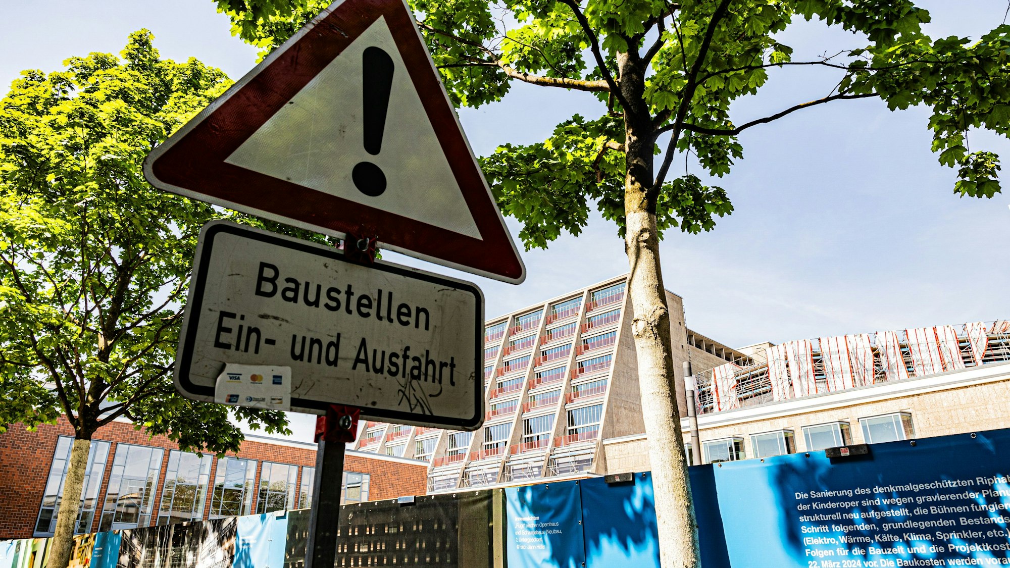 An der Baustelle am Offenbachplatz steht auf einem Verkehrsschild „Baustellen Ein- und Ausfahrt“.
