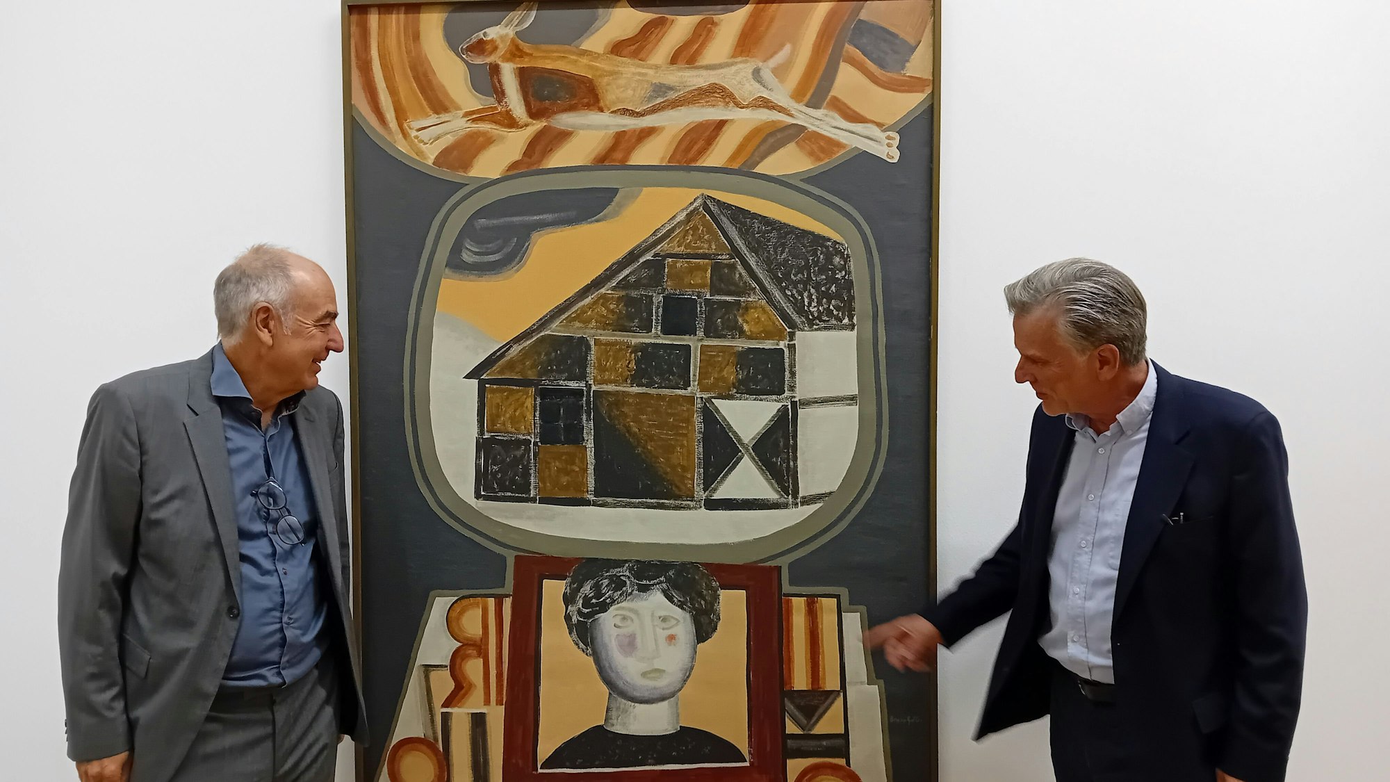 Zwei Herren mit einem Gemälde, auf dem ein Fachwerkhaus, ein Frauenkopf und ein Hase zu sehen sind.