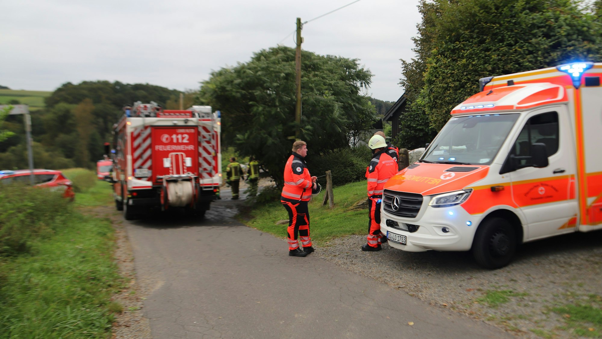 Feuerwehr und Rettungsdienst stehen auf einem Feldweg in Bereitschaft.