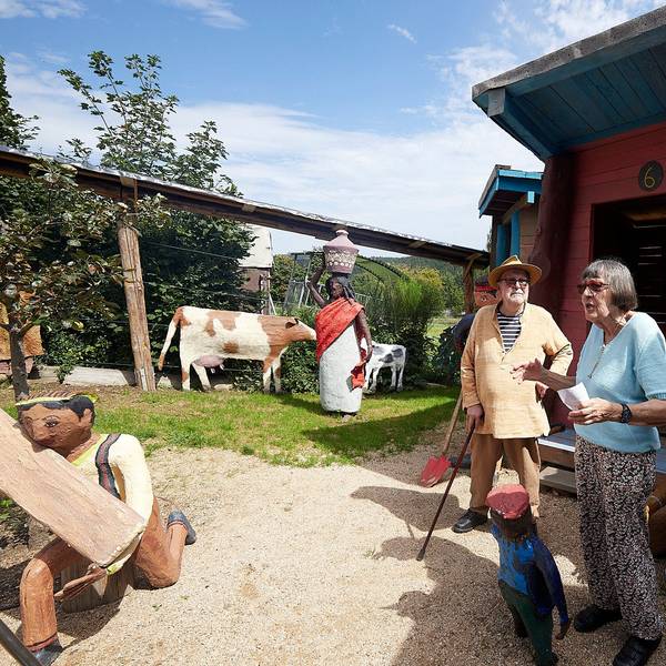 Rita und Paul Greven bei der Eröffnung des Friedensdorfes in ihrem Skulpturenpark. Man erkennt unter anderem Skulpturen von Kühen, einem arbeitenden Mann, einer Frau mit einem Gefäß auf dem Kopf.