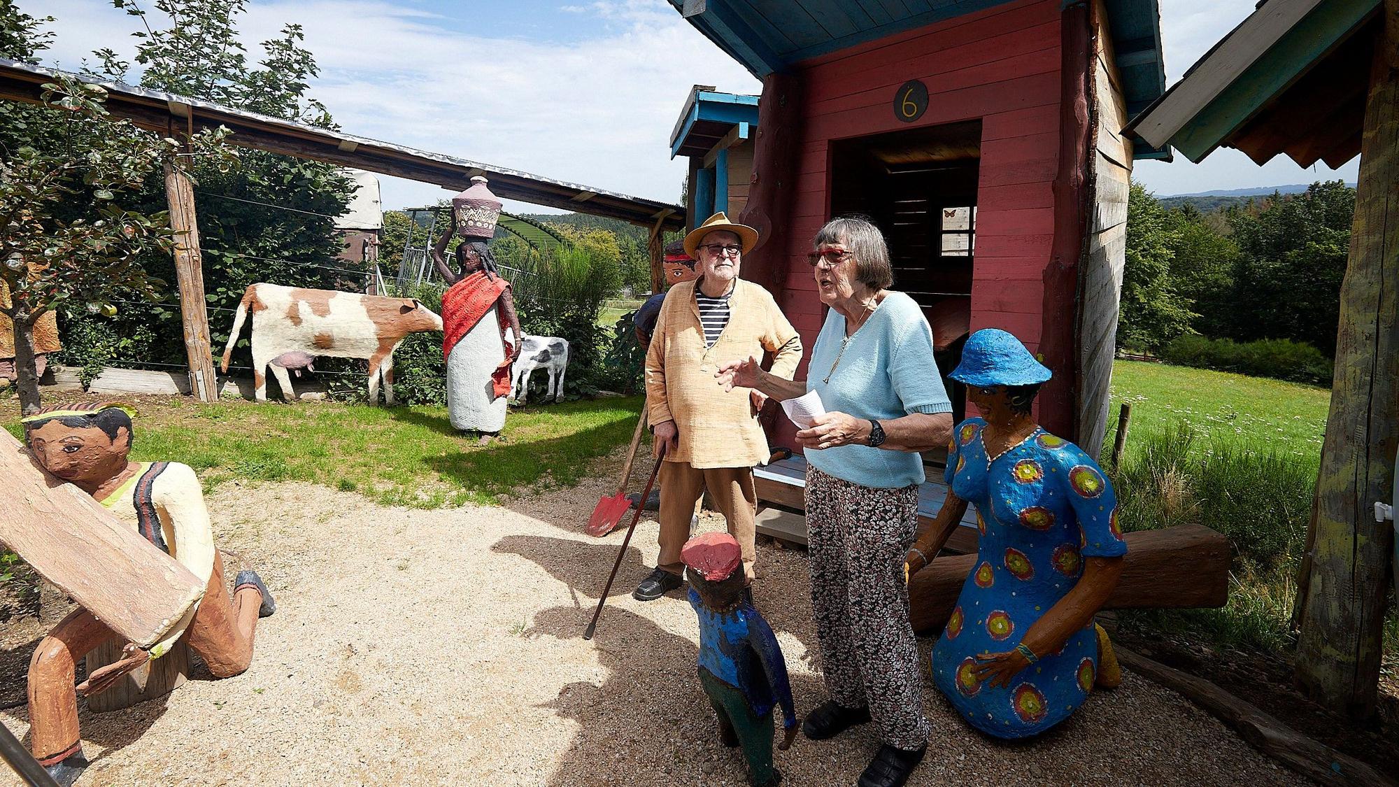 Rita und Paul Greven bei der Eröffnung des Friedensdorfes in ihrem Skulpturenpark. Man erkennt unter anderem Skulpturen von Kühen, einem arbeitenden Mann, einer Frau mit einem Gefäß auf dem Kopf.
