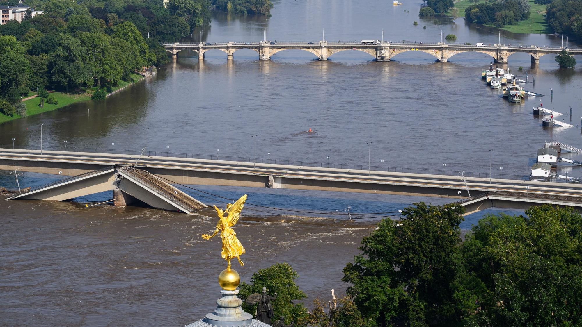Die Hochwasser führende Elbe fließt an der zum Teil eingestürzten Carolabrücke entlang, im Vordergrund ist der Engel „Fama“ auf der Kunstakademie zu sehen.