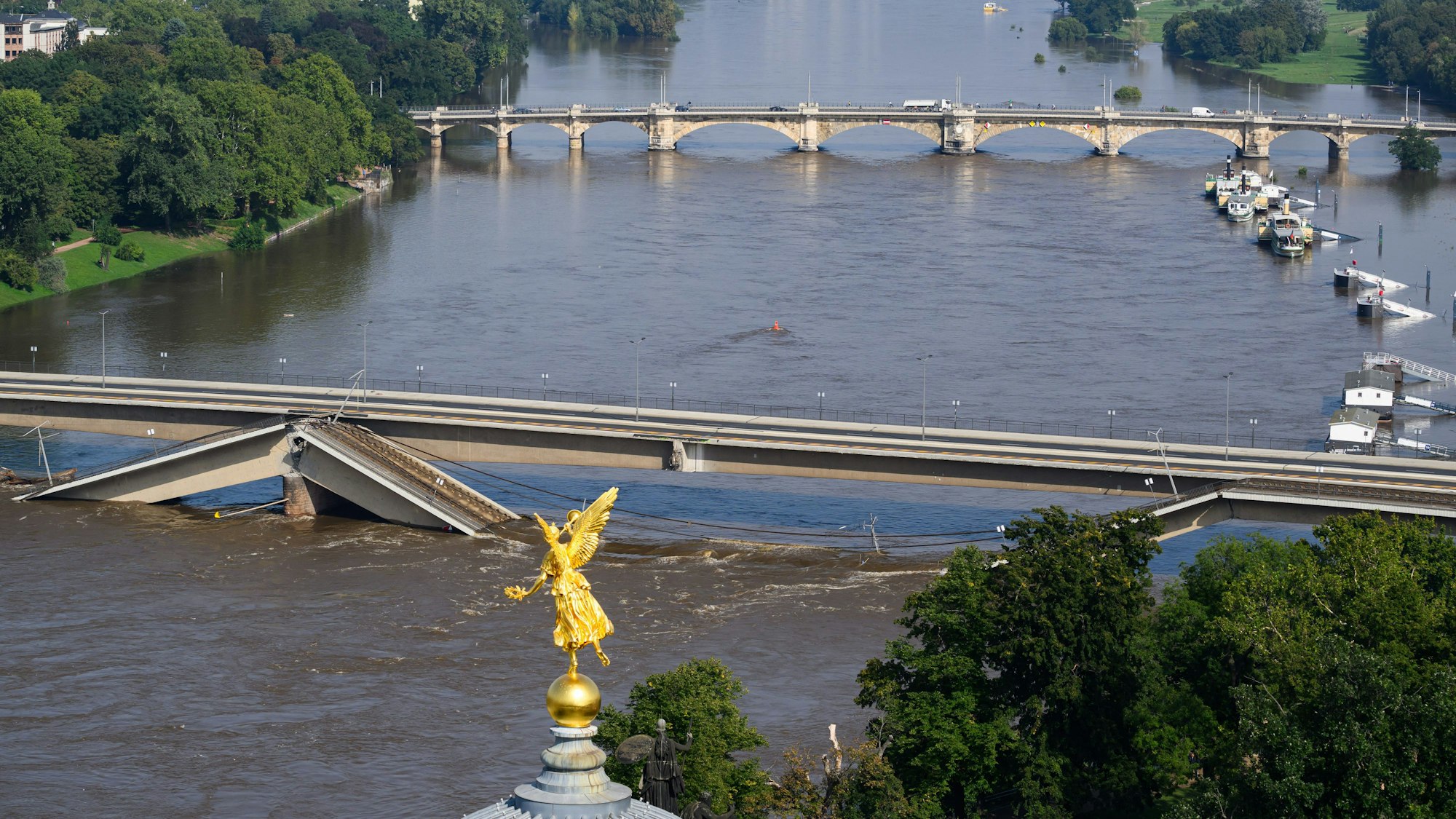 Die Hochwasser führende Elbe fließt an der zum Teil eingestürzten Carolabrücke entlang, im Vordergrund ist der Engel „Fama“ auf der Kunstakademie zu sehen.