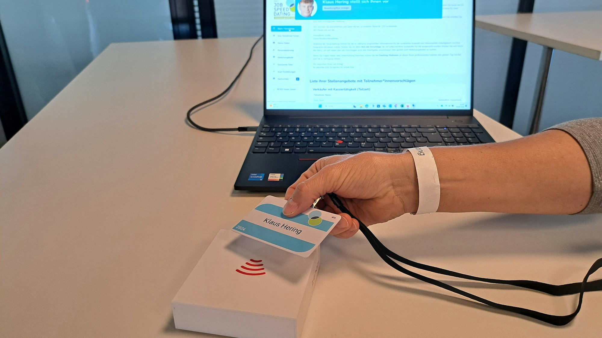 Eine Chipkarte wird über ein Gerät gehalten. Im Hintergrund steht ein Laptop.