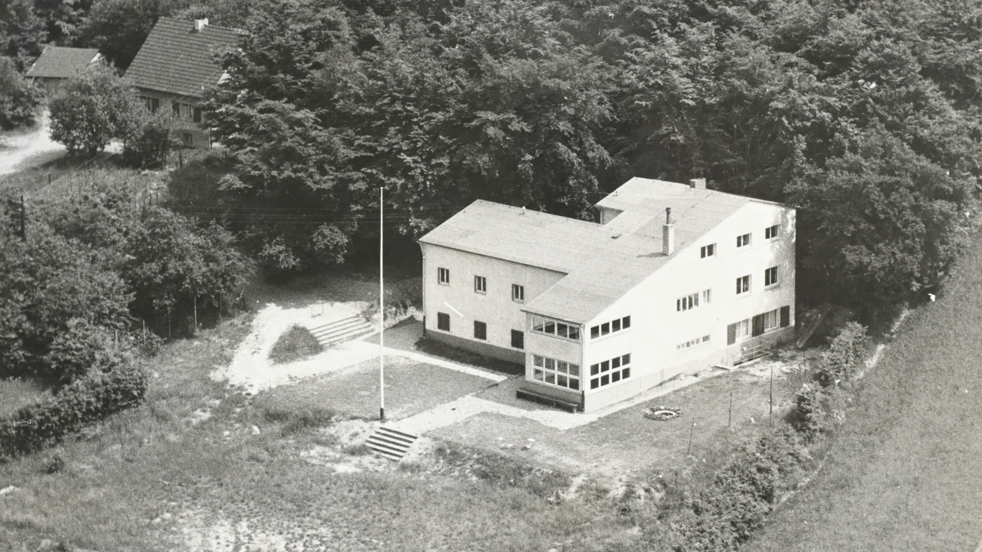 Ein Neubau eines Hauses in den 1930 Jahren. Um das Haus ist viel freies Gelände.