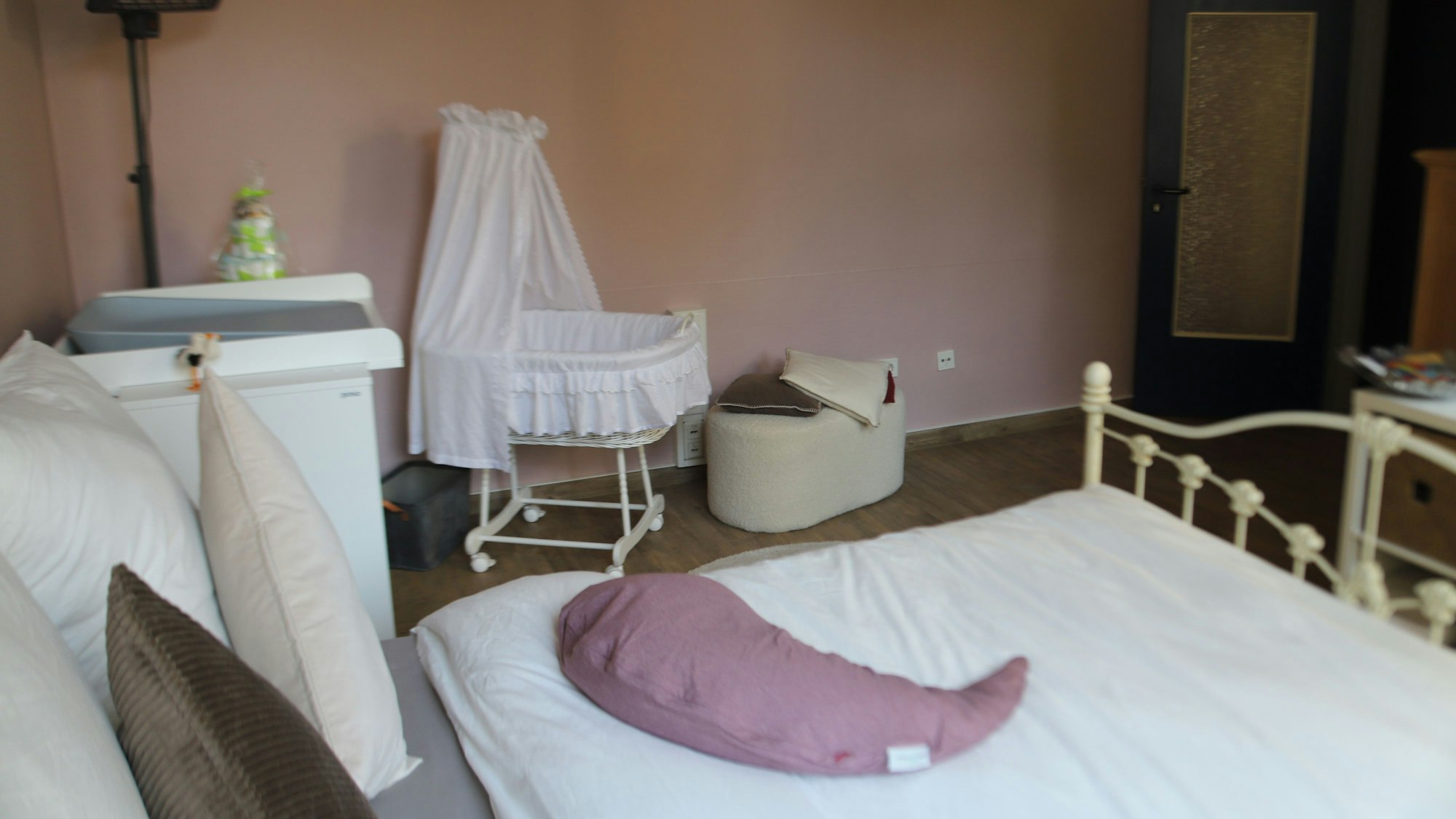 In einem Raum steht neben einem großen Bett ein Kinderbett.