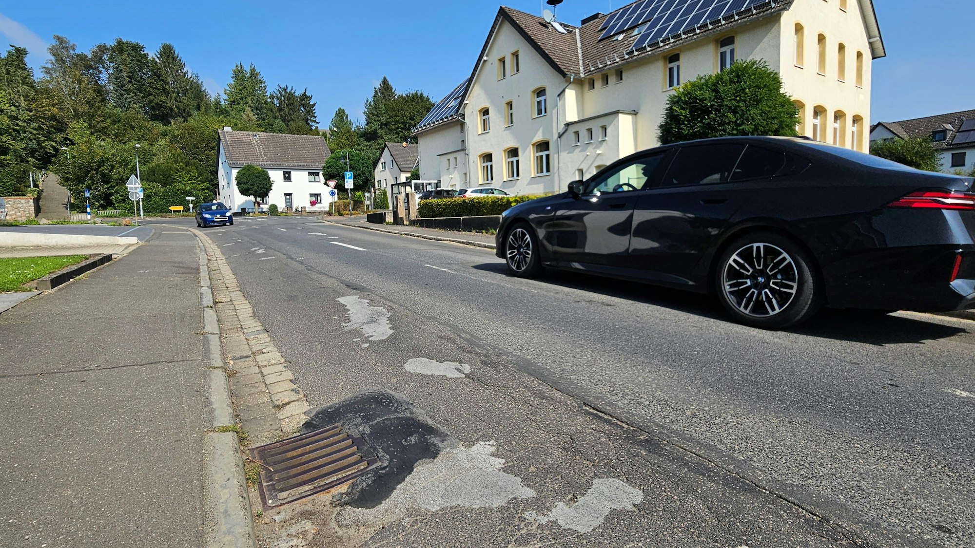 Zu sehen ist die Straße mit vielen geflickten Stellen. Zwei Autos kommen sich entgegen.