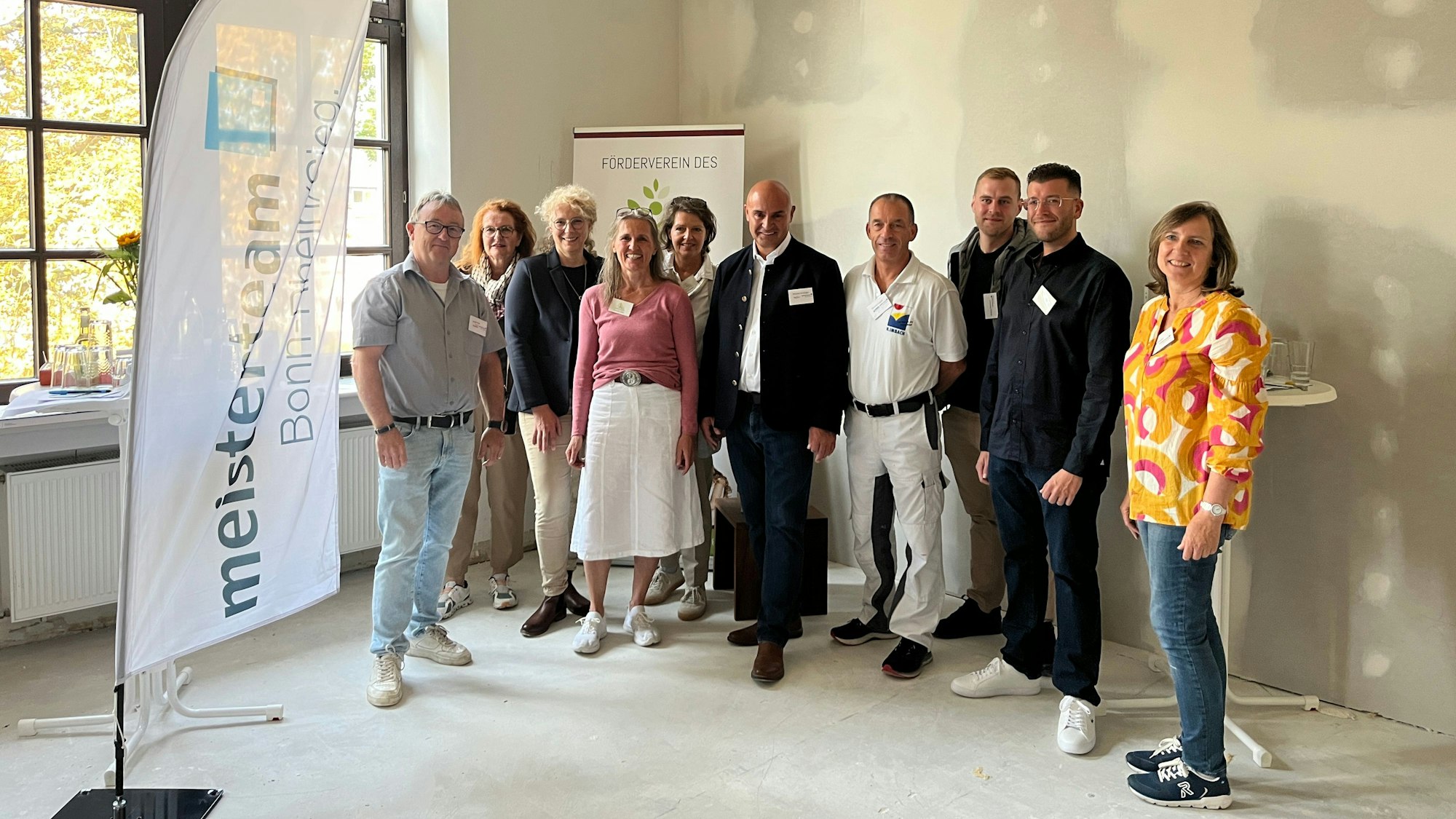 Hebammen und Handwerker stehen in einem Rohbau des Hebammenhauses.