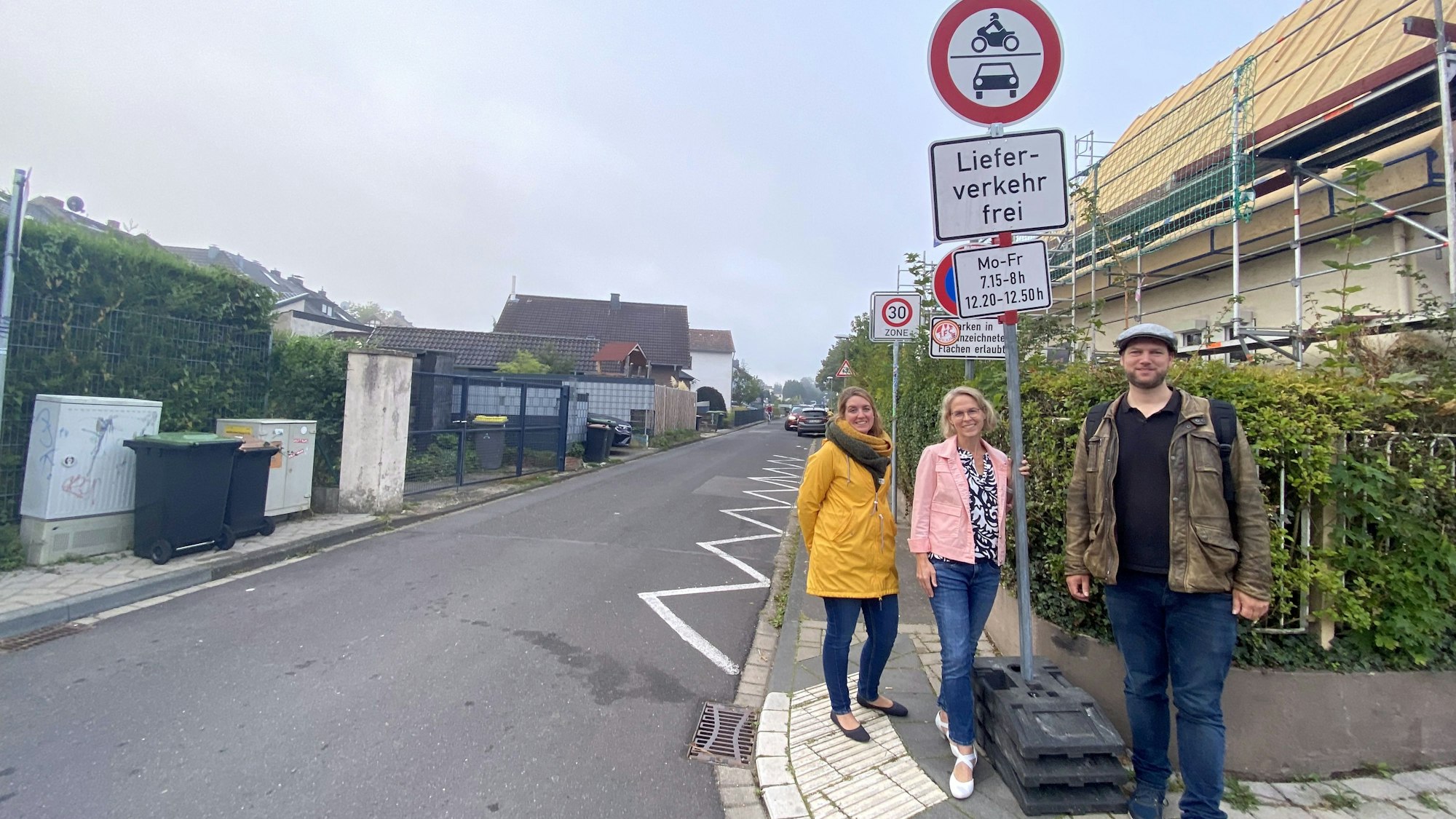 Zwei Frauen und ein Mann an der neuen Beschilderung: Durchfahrtsverbot für motorisierte Fahrzeuge montags bis freitags von 7.15 bis 8 Uhr und 12.20 bis 12.50 Uhr, Lieferverkehr frei.