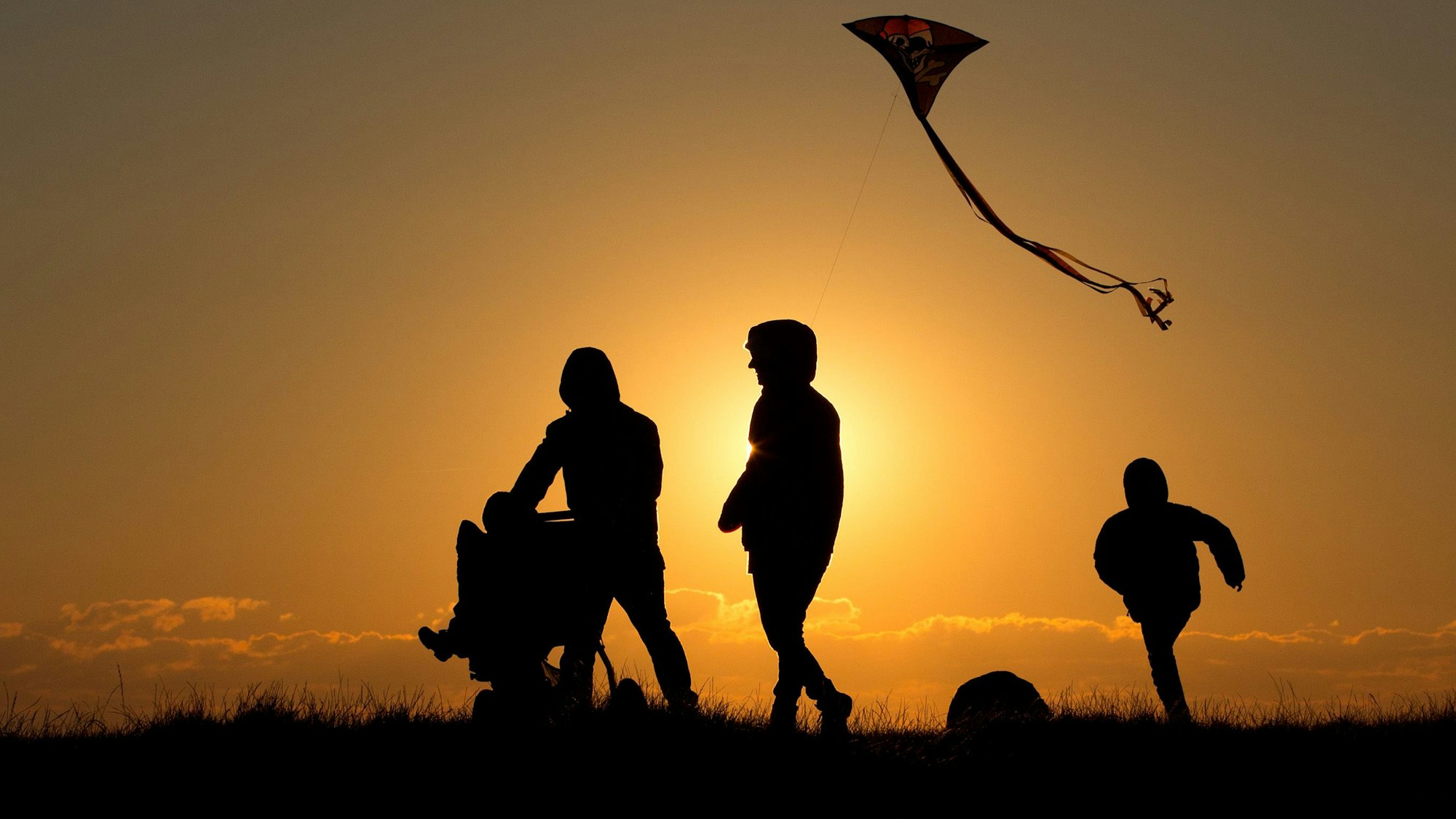 ARCHIV - Eine Familie geht bei Sonnenuntergang über einen Weg (Symbolbild)