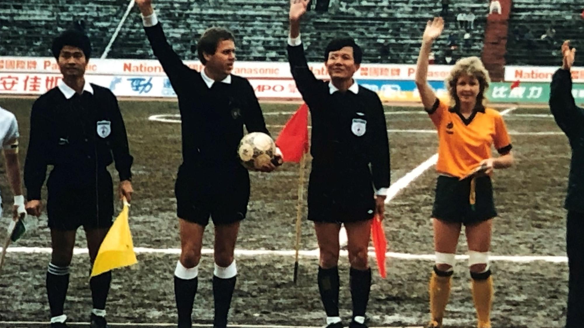 Drei Schiedsrichter und eine Fußballerin in einem gelben Trikot