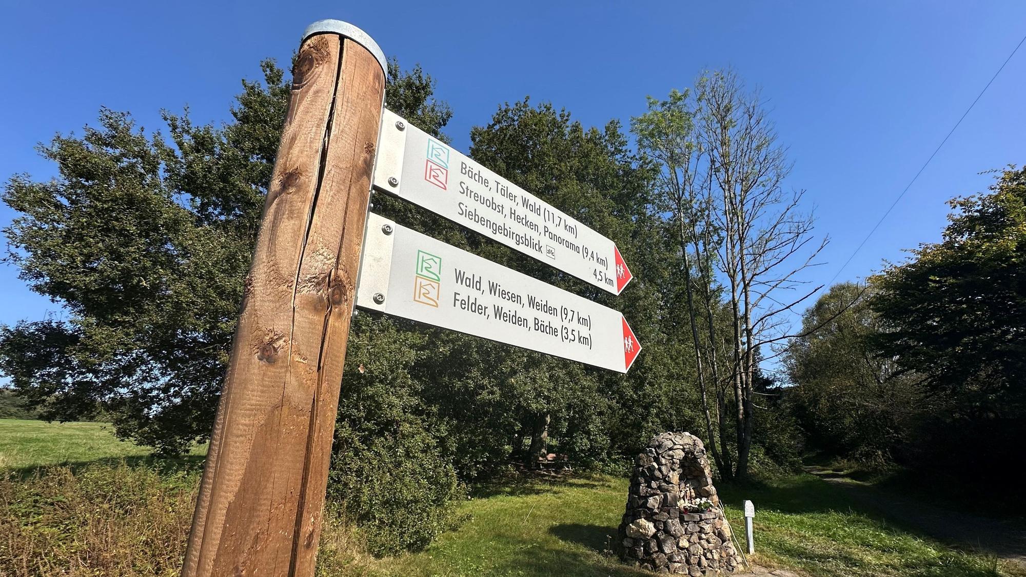 Ein Wegweiser mit zwei Schildern weist auf mehrere Wanderwege hin.
