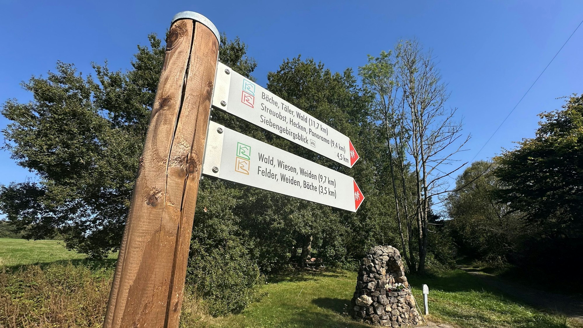 Ein Wegweiser mit zwei Schildern weist auf mehrere Wanderwege hin.