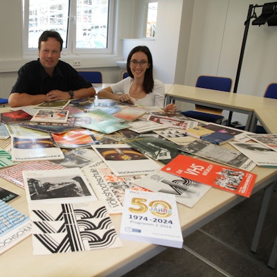 Ein Mann und eine Frau hinter einem Tisch voller Broschüren