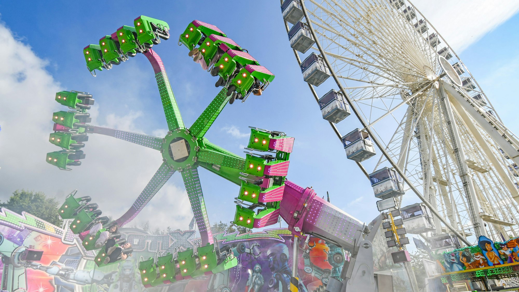 Pützchens Markt. Zu sehen: Ein Fahrgeschäft und ein Riesenrad.