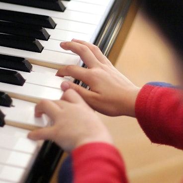 Ein Junge spielt an einem Flügel.