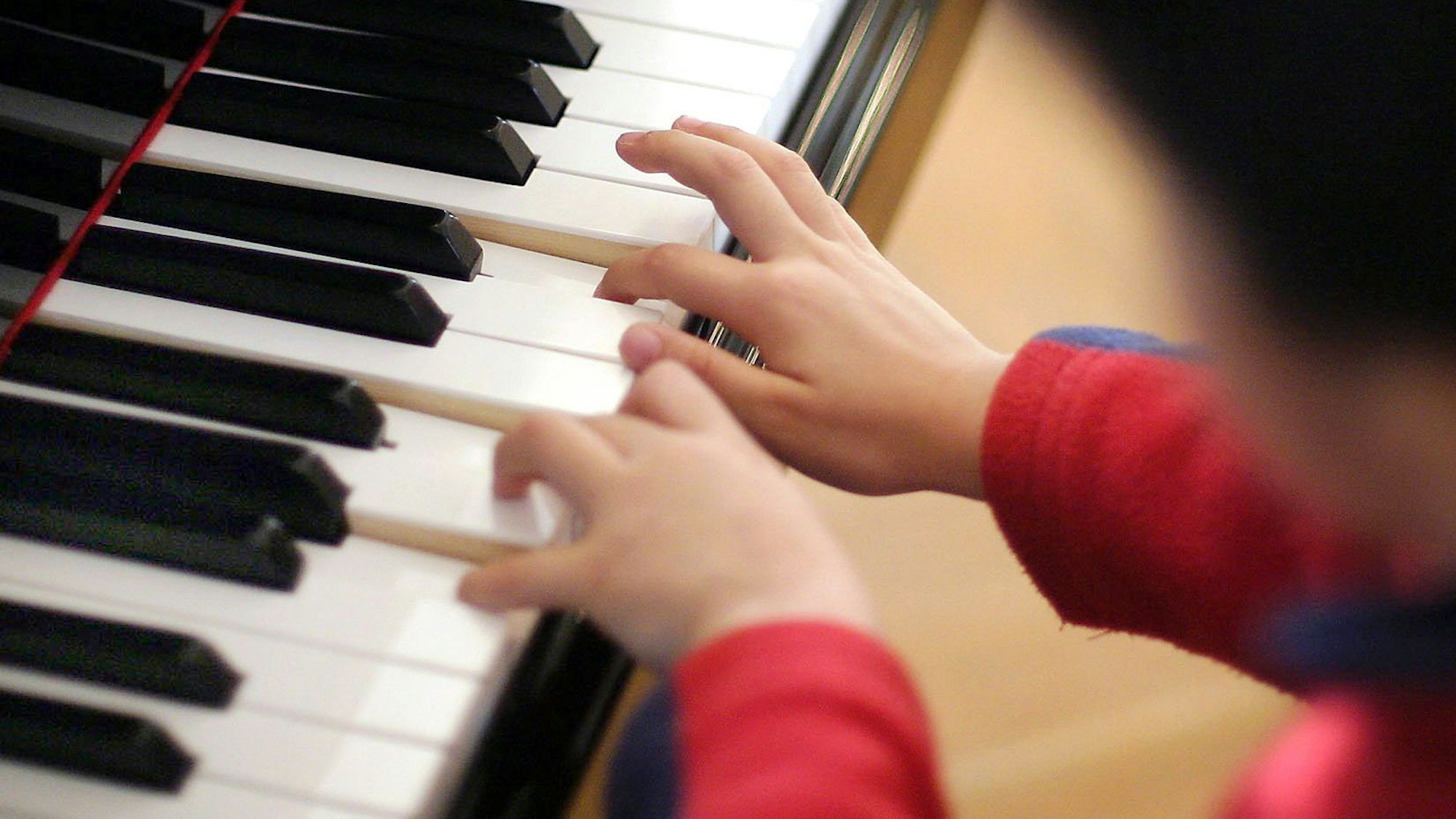 Ein Junge spielt an einem Flügel.